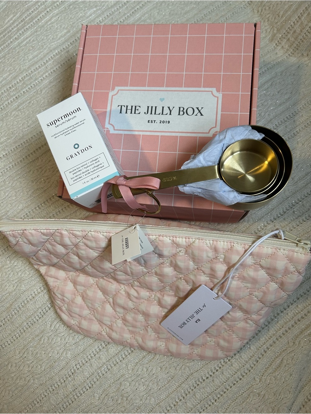Jilly Box items with Pink Quilted Pouch, serum and Gold Measuring cups